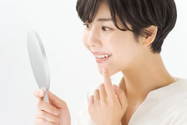 自分の歯を見つめる女性